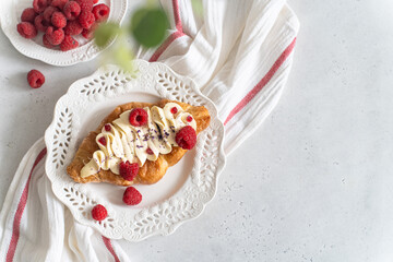 Trendy flat croissant on white plate. Delicious buttery thin croissant with fresh raspberry, cream. french breakfast. Viral Crusty flat croissant recipe, bakery, cafe menu cookbook copy space top view