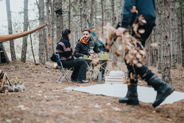 Fototapeta premium Outdoor friends gathered casually for a winter picnic among trees in a peaceful forest setting, emphasizing nature's calm atmosphere.