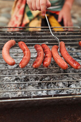Grilling vegetables, sausages, and trout over charcoal in a backyard during summer. Outdoor cooking with real flames and smoke in a cozy home setting