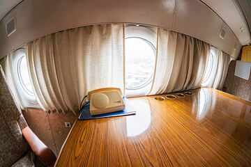Business class airplane cabin interior, wooden floor and curtained windows, empty seats and...