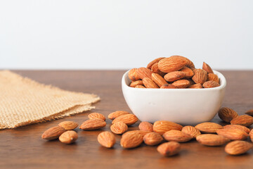 Almonds in white bowl on wooden table background