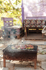 Grilling vegetables, sausages, and trout over charcoal in a backyard during summer. Outdoor cooking with real flames and smoke in a cozy home setting