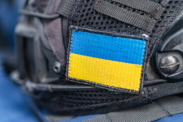 Close-up view of a blue and black paramilitary police helmet with a national flag design patch...