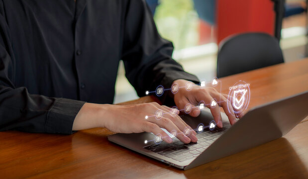 Concept of cybersecurity protection and secure online data management, businessman working on laptop with virtual security shield interface.