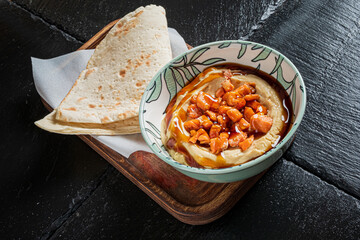 Hummus topped with chickpeas and olive oil, served with warm flatbread on a rustic board