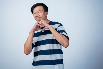 Image Description (under 195 characters):..Asian man in striped shirt smiling and forming a heart...