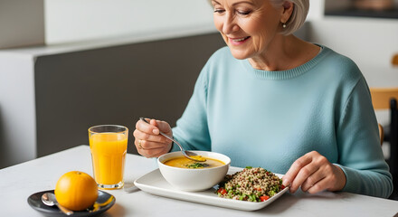 Smiling senior woman enjoying a healthy lunch with soup, rice, and orange juice, promoting wellness and balanced nutrition for a vibrant and active lifestyle in retirement years.