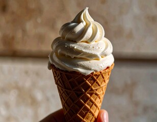 Lody w rożku trzymane w ręku na tle muru