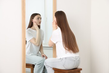 Beautiful woman looking at herself in mirror indoors