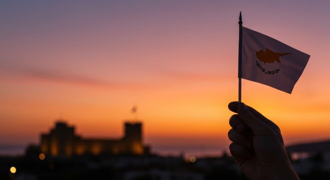 Cyprus flag held against gradient sunset sky with blurred historical landmark
