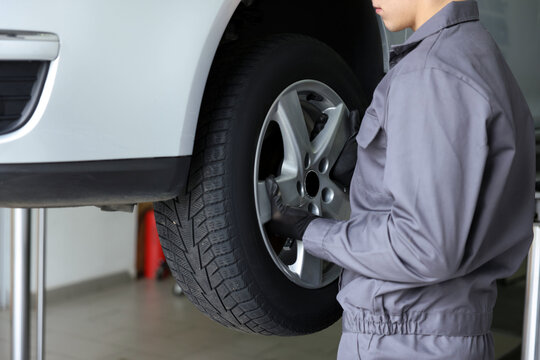 Mechanic changing tire at car service, closeup