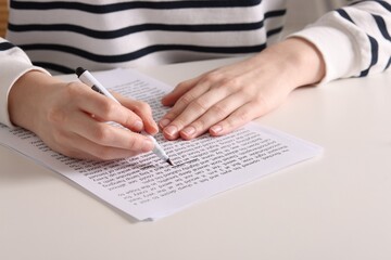 Woman underlining important information with marker at white desk indoors, closeup