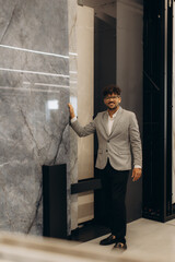 Confident Businessman Standing by Marble Wall in Modern Interior Setting