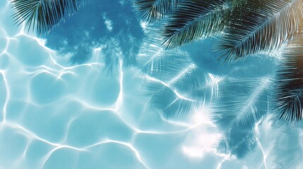 Clear blue swimming pool water reflecting sunlight with palm tree shadows and fronds on the surface.