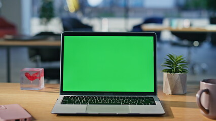 Modern green screen laptop displayed on work desk closeup. Chroma key computer
