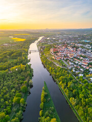 Aerial view reveals the beautiful confluence of the Vltava and Labe rivers close to Melnik, Czechia. Lush green banks and charming towns create a picturesque landscape during sunset.
