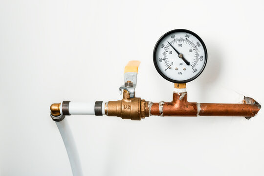 PSI temperature gauge for hot water heating system. Copper pipe with psi and kPA gauge and water shut off. Part of Non-potable closed-loop heating system in residential home. Selective focus.