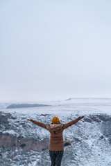 Traveller woman raise her arms against snowy canyon.