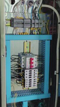 A close-up shot captures the intricate and technical mood of an open electrical control panel, revealing a complex network of wires, terminals, and circuit breakers, essential for industrial