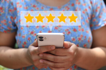 A person holding a smartphone with floating icons of five-star ratings and customer reviews, symbolizing positive feedback, user satisfaction, and digital engagement through mobile platforms.
