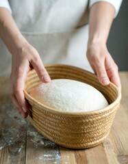 Woman's hands putting bread dough into a basket.
