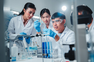 A diverse team of young scientists conducts a chemistry experiment, carefully analyzing blue...