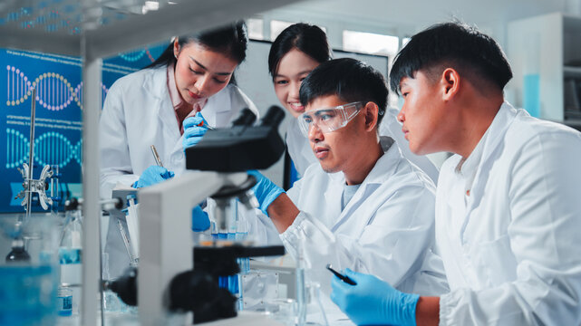 A diverse team of young scientists conducts a chemistry experiment, carefully analyzing blue liquids in test tubes, demonstrating teamwork, focus, and precision in a modern laboratory setting.