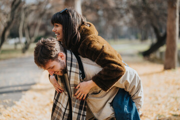 A joyful couple embracing happiness and love, playfully capturing the spirit of autumn outdoors.