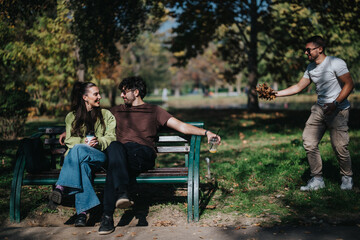 A group of cheerful friends spending time outdoors. A couple sits on a park bench while another...