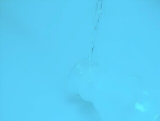 Verser de l'eau dans un verre avec une bouteille en plastique avec un bouchon solidaire en gros plan sur fond bleu