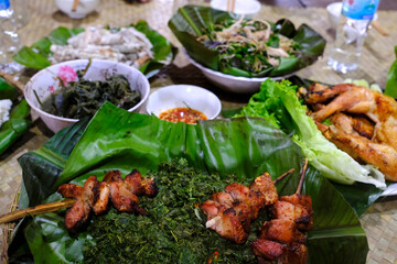 Traditional festive meal in a village on the highlands. Rice cooked over a wood fire in a bamboo pot. Kontum. Vietnam.