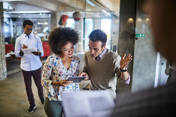 Happy business colleagues using a tablet for a presentation in a modern office