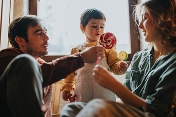 A family enjoys time together, sharing a sweet treat in a warm, cozy room with natural light. A depiction of love, togetherness, and joyful domestic life.