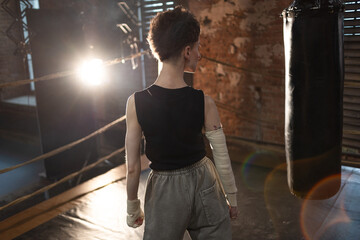A female boxer with short hair and a black T-shirt. athletic appearance, pause after an intense...