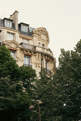 Fototapeta premium Ornate Parisian Haussmann Building Facade, Low Angle View with Trees