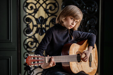 Obraz premium Young Boy Playing Acoustic Guitar with Focused Expression