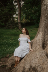 Naklejka premium Woman in a White Dress is walking in a park, soft-focus trendy image. 