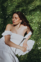 A young woman relaxing in nature, lying on the grass, soft focus trendy image