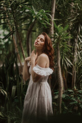 Fototapeta premium Woman in a White Dress is walking in a park, soft-focus trendy image. 