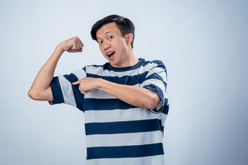 Asian man in striped shirt showing off his biceps with a proud facial expression, lips pursed in a...