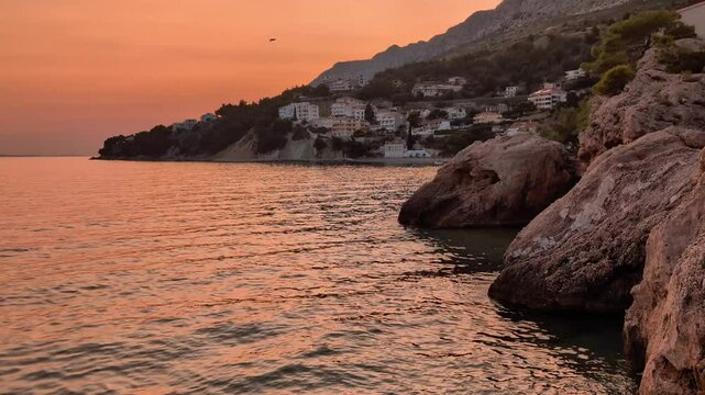 beautiful coastal landscape sunrise scenery, natural rock formations at sandy beach, with mountain Biokovo in background, Mimice, Dalmatia, Croatia, Adriatic sea at Mediterranean