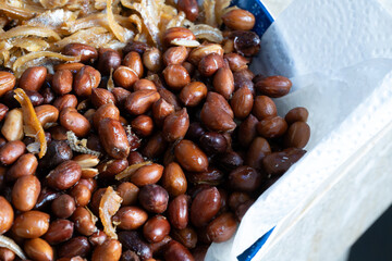 A close-up view of a traditional Malaysian side dish featuring crispy fried anchovies (ikan bilis) and roasted peanuts served on a blue plate. 