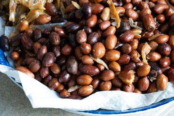 A close-up view of a traditional Malaysian side dish featuring crispy fried anchovies (ikan bilis)...