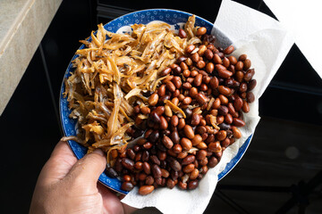 A close-up view of a traditional Malaysian side dish featuring crispy fried anchovies (ikan bilis)...