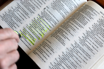 Fototapeta premium Man studying the Bible and highlighting important passages. Bible study.