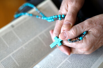 Man praying the rosary and the Bible at home.