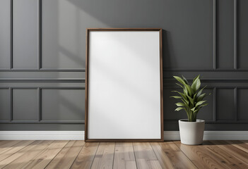 Empty picture frame mockup leaning against a dark grey wall with a potted plant.