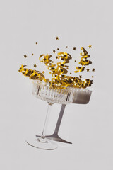 Champagne glass, serpentine and golden stars on white background. Shiny greeting card for Christmas, wedding or birthday party.