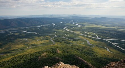 Elevated view Green valleys and winding river under bright, cloudy sky