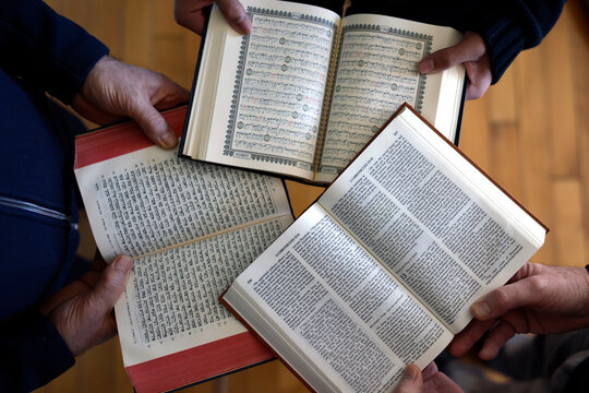 Three monotheistic religions. A Christian, a Jew, and a Muslim reading the Bible, the Torah, and the Quran. Symbol of peace and interfaith dialogue.